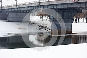 Reinforced concrete bridge over the river and snow. strong modern water crossing for cars and people