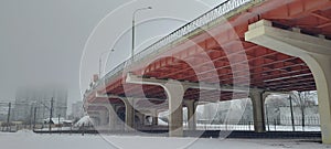 Reinforced concrete bridge in winter. Urban landscape with a red bridge.