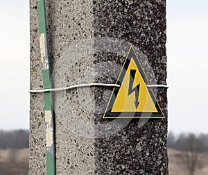 Reinforced concrete electricity pole with sign warning caution electricity shock risk high voltage keep out hazard