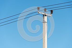 reinforced concrete pillar with high-voltage wires against a clear blue sky. Transmission of electricity by wires over long