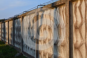 Reinforced concrete wall with barbed wire.
