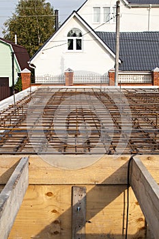 reinforcement of concrete with metal rods connected by wire. view of wooden formwork with metal holders, which will be filled with