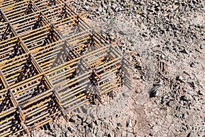 reinforcing frame mesh covered with rust lies on the ground, waiting to be raised to the mounting horizon