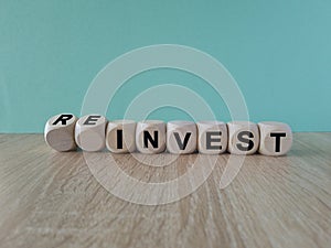 Reinvest symbol. Inverted wooden cubes with words \'invest - reinvest\'.