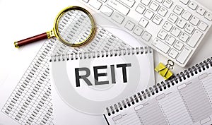 REIT Real Estate Investment Trust, text written on a notebook on chart with keyboard and planning