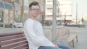 Rejecting Young Man Shaking Head in Denial while Sitting on Bench