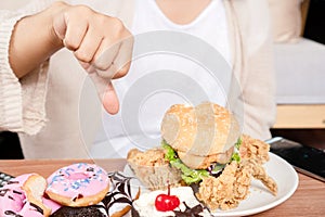 Rejection of fast food concept with woman hand showing dislike, thumbs down with many junk food