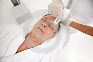 Rejuvenating facial treatment. Top view of a mature man getting lifting therapy massage in a beauty SPA salon. Exfoliation,