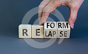 Relapse or reform symbol. Businessman turns cubes and changes the word `relapse` to `reform`. Beautiful grey background. Busin