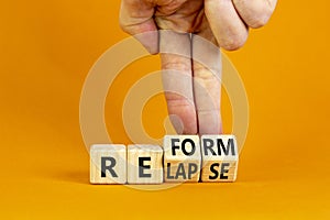 Relapse or reform symbol. Businessman turns cubes and changes the word `relapse` to `reform`. Beautiful orange background.