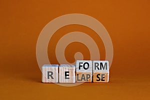 Relapse or reform symbol. Turned wooden cubes and changed the word `relapse` to `reform`. Beautiful orange background. Busines