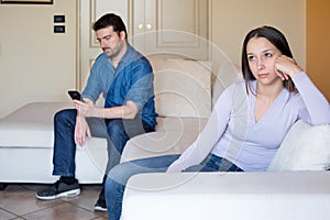 Sad and bored young woman sitting on the sofa