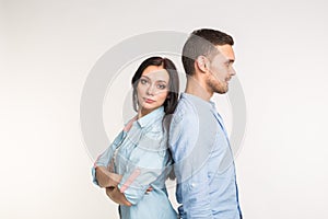 Relationship, family conflict and people concept - young couple standing back to back on white background