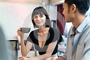 Relationship of interracial young couple drinking coffee in cafe restaurant together. Beautiful Caucasian woman holding coffee cup