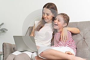 Relationship of mother and daughter concept. Mom and little girl using laptop computer to play game togethers in weekend at home