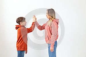 Relationship, mothers day, children and family concept - teen boy giving high five to his mom on white background