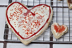 Relationship pair of heart sugar cookies with white frosting and red sprinkles. representing relationship.