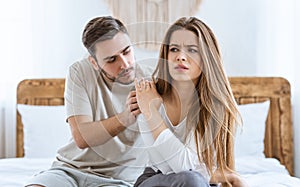 Relationship problems. Husband calms his wife, upset woman rejects boy on bed photo