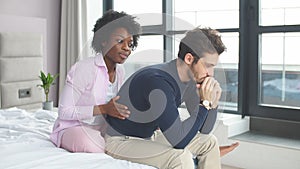 Relationship problems. Frustrated young mixed raced couple sitting in bed.