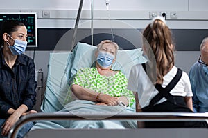 Relatives wearing masks accompanying senior lady in recovery room