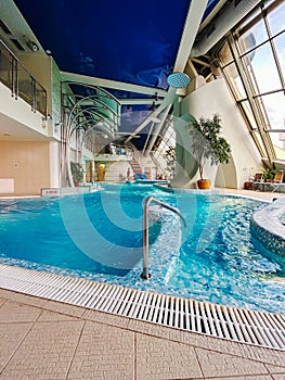 Relax in an aqua oasis with a azure pool under a blue ceiling in a building