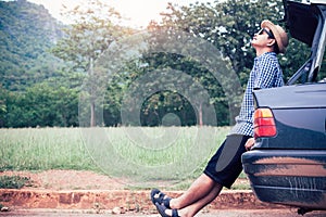 Relax asian man sitting inside car trunk with green nature background