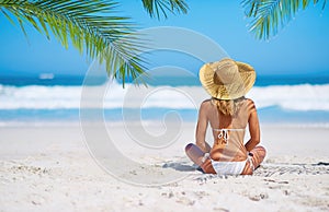 Relax, back view of a woman on the beach and sitting on the sand, Summer vacation or holiday break, freedom or adventure