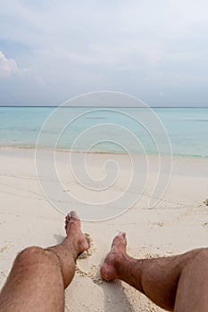 Relax on the beach. In the frame of the guy`s feet