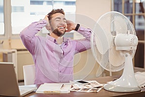 Relax businessman sitting by electric fan