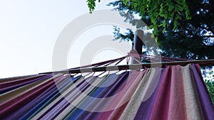 Relax on Colorful hammock on the tree in the forest. Camping night with fabric with rainbow colors. Home relaxing in the garden