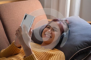 Relax, de-stress, holiday, happy, Asian woman relaxing at home listening to music from smartphone and laptop happily