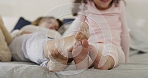 Relax, feet of mother and daughter on bed for morning love, fun and bonding with security in home. Smile, sleep and wake