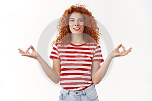 Relax gathering patience. Smiling relieved happy gorgeous redhead curly woman striped t-shirt hands spread sideways