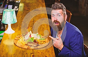 Relax after hard working day. Businessman formal suit sit at bar counter. Man received meal with fried potato fish