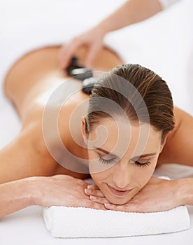 Relax, hot stone massage and woman at spa for health, wellness and luxury holistic treatment. Self care, peace and girl