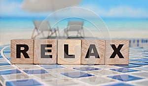 Relax - an inscription on wooden cube blocks on sunny beach beckground with reflection