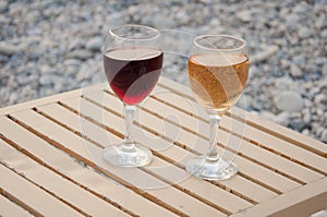 Relax on pebble beach. Two wineglass stand on table in afternoon