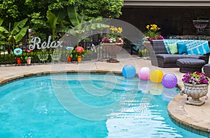 Relax by the pool - flowers and plants and decor by the pool with a big RELAX metal sign on the fence and multi-colored balls floa photo