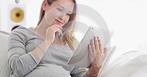 Relax, pregnant or woman research on tablet in living room in house for social media, reading email or ebook. Internet