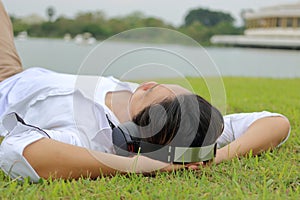 Relax time concept. Young Asian man listening to music with headphone in nature background.