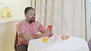relax time at home in evening, portrait of african man surfing internet by smartphone, drinking tea