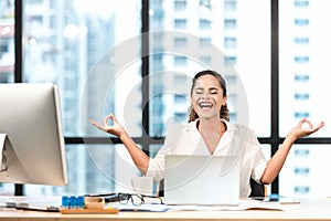 Relax time.  Successful smilling business woman relaxing and  meditating after working in modern office, mindful peaceful and prac photo