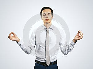 Relax and tranquility concept with handsom man with closed eyes in zen pose isolated on light grey wall background, close up