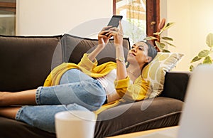 Relax woman on her phone with social media while on the sofa in house. Content female browsing internet with app while