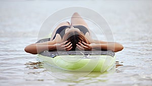 Relax, woman or surfer on water at a beach on holiday vacation resting on a surfboard in Bali. Freedom, thinking or