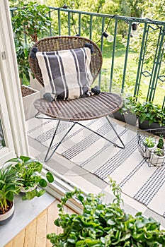 Relax zone on a balcony with a chair, rug and plants.