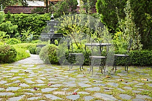 Relaxation area in a English garden. Chair with blurry fountain