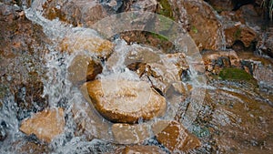 Relaxation background flowing mountain stream water on orange rocks slow motion