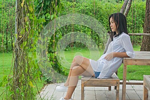 Relaxation Concept : Asian woman sitting on wooden chair at outdoor garden.