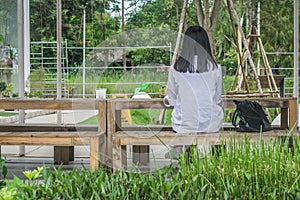 Relaxation Concept : Back view woman sitting relax on wooden chair at outdoor garden.